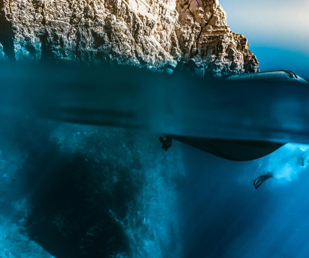 Apneísta en cueva submarina iluminada por la luz. Fotografía única de freediving.